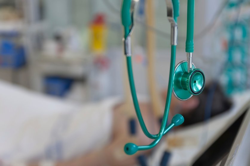 Green stethoscope, on background patient  connected to medical ventilator in ICU in hospital, a place where can be treated patients with pneumonia caused by coronavirus covid-19. (Green stethoscope, on background patient  connected to medical ventilat