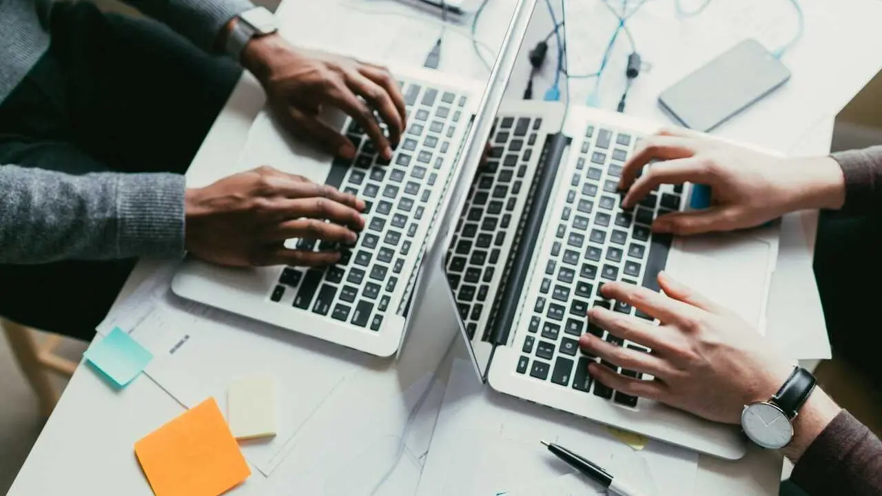View of an african american and caucasian man collaborating on two laptops