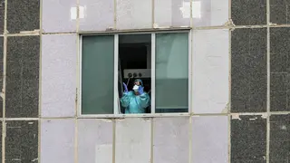 Una sanitaria del Hospital de La Paz totalmente protegida saluda y agradece el apoyo desde una de las ventanas del centro donde se lucha contra el coronavirus, en Madrid (Espa&ntilde;a), a 18 de marzo de 2020.
