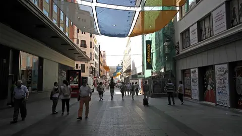 Turistas y vecinos de la zona Centro de Madrid pasean por la calle Preciados bajo la sombra gracias a los toldos instalados.