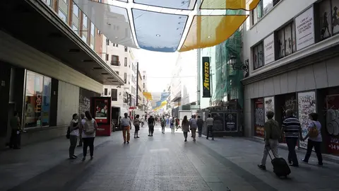 Turistas y vecinos de la zona Centro de Madrid pasean por la calle Preciados bajo la sombra gracias a los toldos instalados