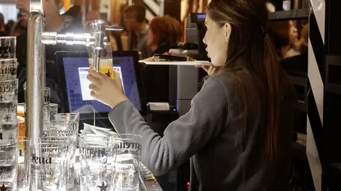 Una cambrera serveix una cervesa en un bar