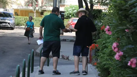 Un hombre le da una botella de agua a un anciano, mientras pasean por una calle de Madrid.