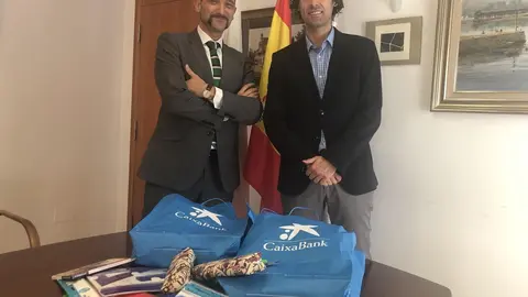 El alcalde de Astillero, Javier Fern&aacute;ndez Sober&oacute;n, y el director de la oficina de Caixabank en la localidad, &Iacute;&ntilde;igo Crespo, con lotes de material escolar que la Obra Social &ldquo;la Caixa&ldquo; ha proporcionado para las familias necesitadas del municipi