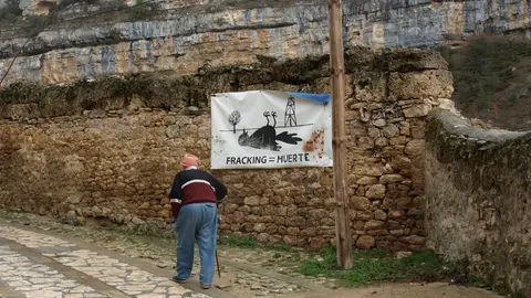 Hombre camina junto a cartel contra el fracking 
