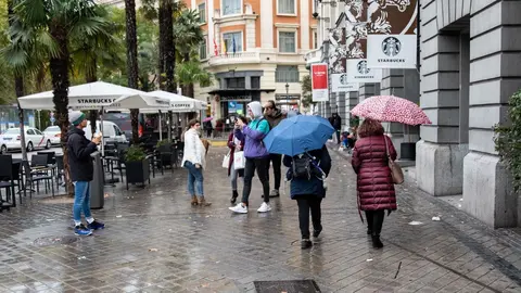 Varias personas pasean por la calle con un paraguas debido a la lluvia