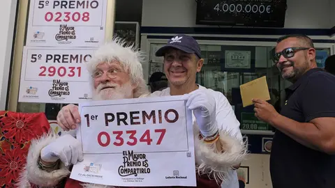 El propietario (con gorra) de la administraci&oacute;n de Loteria La Esfinge, de calle Ripoche n1 de Las Palmas de Gran Canaria, celebra, con algunos de los agraciados, que ha repartido parte del Gordo y el quinto premio del Sorteo de Loter&iacute;a Nacional.  