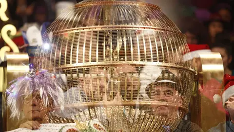 Personas disfrazadas detr&aacute;s de un bombo esperan en el Teatro Real de Madrid para disfrutar del Sorteo Extraordinario de la Loter&iacute;a de Navidad. 