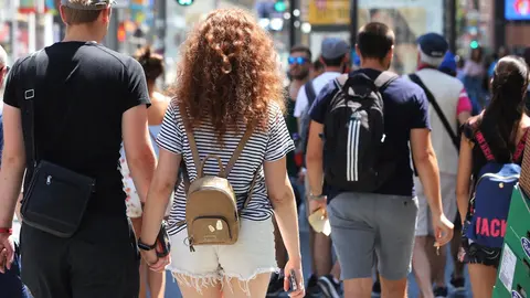 Una pareja cruza de la mano un paso de peatones de la Gran V&iacute;a de Madrid.