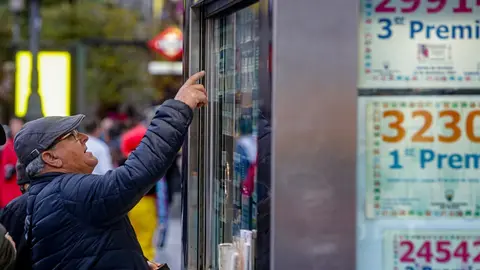 Un hombre se&ntilde;ala el d&eacute;cimo de Loter&iacute;a de Navidad que quiere comprar en una Administraci&oacute;n en la plaza de Puerta del Sol, en Madrid (Espa&ntilde;a), a 18 de noviembre de 2019.