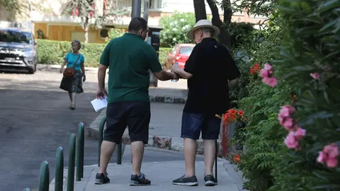 Un hombre le da una botella de agua a un anciano, mientras pasean por una calle de Madrid.
