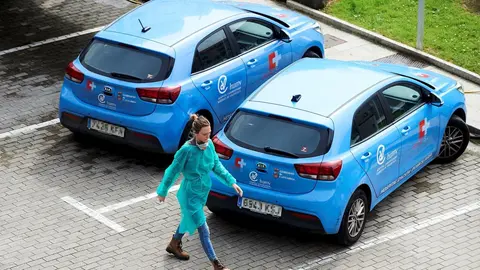 Una profesional sanitaria pasa al lado de veh&iacute;culos de hospitalizaci&oacute;n domiciliaria del Hospital Universitario Marqu&eacute;s de Valdecilla 