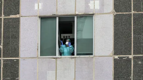 Una sanitaria del Hospital de La Paz totalmente protegida saluda y agradece el apoyo desde una de las ventanas del centro donde se lucha contra el coronavirus, en Madrid (Espa&ntilde;a), a 18 de marzo de 2020.