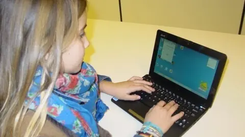 Una escolar, con un ordenador port&aacute;til.
