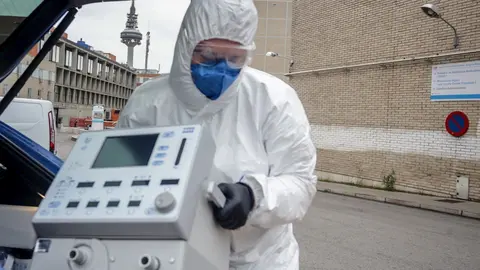 Un t&eacute;cnico protegido con un traje, guantes y mascarilla en el Hospital Gregorio Mara&ntilde;&oacute;n, saca un respirador del maletero de su coche antes de montarlo en el Hospital, elemento imprescindible para muchos pacientes enfermos de coronavirus, en Madrid