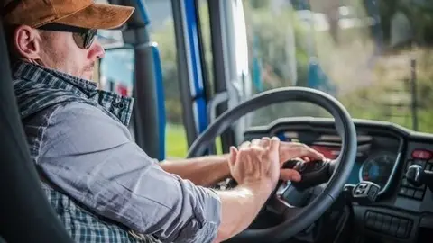 Caucasian Truck Driver in His 30s in the Semi Cabin. Modern Transportation Job.