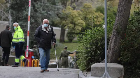 Un hombre con muleta y mascarilla pasa junto al &aacute;rea donde soldados del Mando de Ingenieros de Salamanca del Ej&eacute;rcito de Tierra, una unidad de 34 militares, instalan un hospital provisional de entre 60 y 70 camas en el Hospital Gregorio Mara&ntilde;&oacute;n