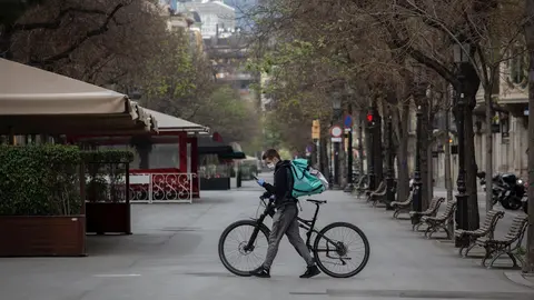 Un trabajador de Deliveroo en bicicleta por una calle de Barcelona, vac&iacute;a durante el primer d&iacute;a laborable de la segunda semana desde que se decret&oacute; el estado de alarma en el pa&iacute;s a consecuencia del coronavirus, en Barcelona.