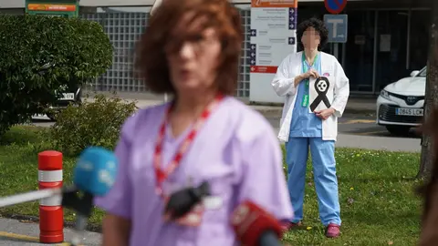 Una sanitaria del Osakidetza (servicio vasco de salud)  del Hospital de Galdakao responde a los medios mientras otra profesional sostiene un lazo negro de luto en recuerdo a la enfermera de 52 a&ntilde;os fallecida por Covid-19