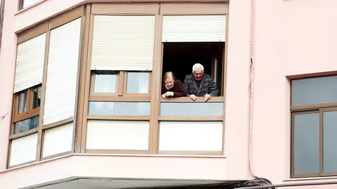Unos ancianos confinados se asoman a su ventana durante la cuarentena por el coronavirus 
