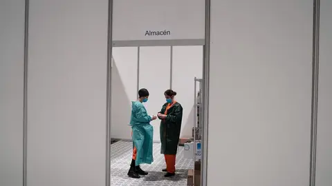 Dos trabajadores sanitarios hablan en las instalaciones del hospital de campa&ntilde;a instalado en IFEMA 