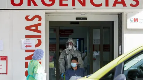 Un sanitario empuja una silla de ruedas con un enfermo leve de Covid-19 para su posterior traslado desde el Hospital de La Princesa al hospital de campa&ntilde;a en IFEMA 