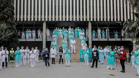 Sanitarios protegidos con mascarillas aplauden conmocionados tras el minuto de silencio en la entrada del Hospital Doctor Peset por la t&eacute;cnica de enfermer&iacute;a fallecida por coronavirus, en Valencia/Comunidad Valenciana (Espa&ntilde;a) a 6 de abril de 2020.