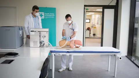Dos operarios cl&iacute;nicos del proyecto de respiradores de SEAT muestran el funcionamiento de un respirador que han fabricado para los contagiados por coronavirus en un maniqu&iacute; de simulaci&oacute;n m&eacute;dica en las instalaciones de SEAT de Martorell