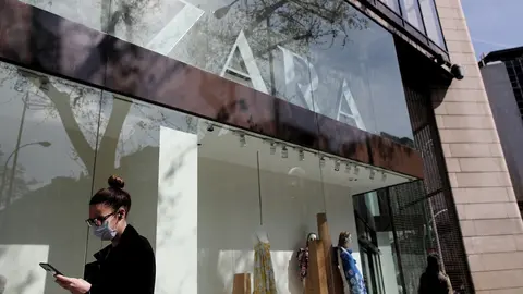Una mujer con mascarilla pasa junto al escaparate de la tienda Zara de la Calle Princesa de Madrid del grupo Inditex,