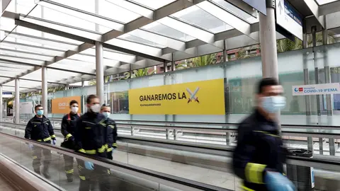 Bomberos de la Comunidad de Madrid protegidos con mascarilla caminan por las inmediaciones del hospital de campa&ntilde;a montado en IFEMA para contagios con coronavirus. En Madrid, (Espa&ntilde;a), a 11 de abril de 2020.