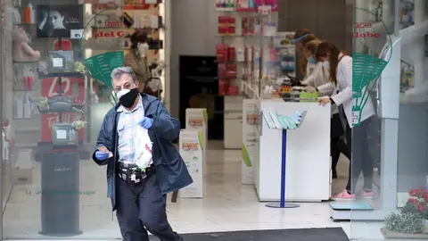 Un hombre protegido con mascarilla y guantes sale de una Farmacia. En Madrid (Espa&ntilde;a) a 14 de abril de 2020.