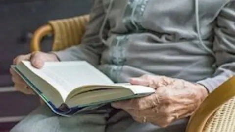 Imagen de archivo de un anciano leyendo un libro en una residencia.