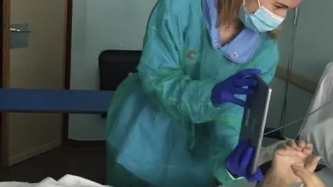 Trabajadora social ayuda a paciente con coronavirus en el hospital Sierrallana a hablar con sus familiares