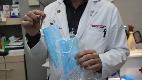 Un farmac&eacute;utico muestra una de las mascarillas que se venden en su farmacia durante el segundo mes de confinamiento, en Madrid (Espa&ntilde;a) a 20 de abril de 2020.