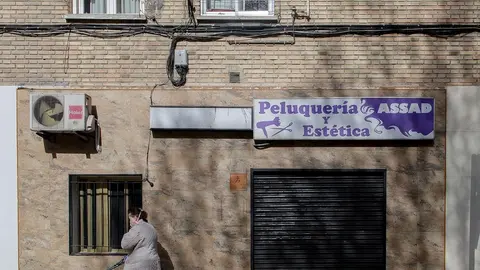 Una mujer pasea a un perro cerca de una peluquer&iacute;a cerrada durante el primer d&iacute;a laborable desde que se decret&oacute; el estado de alarma en todo el territorio nacional a consecuencia del coronavirus, en Alcorc&oacute;n (Madrid), a 16 de marzo de 2020.