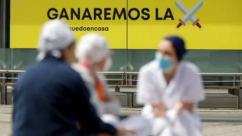 Sanitarios junto a un cartel en el que se lee 'Ganaremos la batalla' en el hospital de campa&ntilde;a de IFEMA, en el que los pacientes de coronavirus son ahora atendidos &uacute;nicamente en el Pabell&oacute;n 9 tras el cierre del 7 al bajar la presi&oacute;n asistencial y que esta