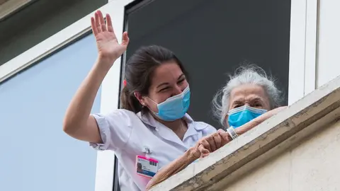 Una sanitaria ayuda a una paciente mayor a salir a la ventana para rendir homenaje a los sanitarios en el Hospital Fundaci&oacute;n Jimenez Diaz durante la pandemia de Covid-19 en Abril 20, 2020 in Madrid, Espa&ntilde;a