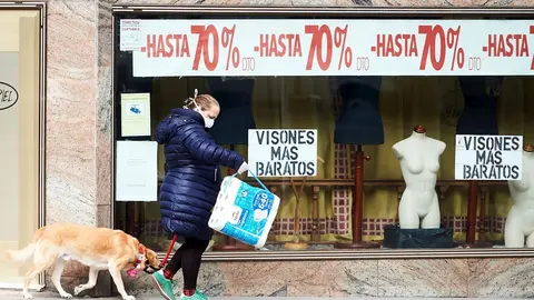 Una mujer pasando por delante de una tienda cerrada en Santander. Archivo