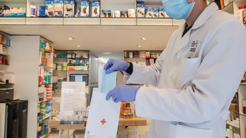 Un farmac&eacute;utico da una mascarilla durante el reparto de mascarillas gratuitas contra el Covid-19 a mayores de 65 a&ntilde;os y colectivos de riesgo que ayer arranc&oacute; en la Comunitat Valenciana. Despu&eacute;s de algunas colas a primera hora en determinadas poblaciones, 