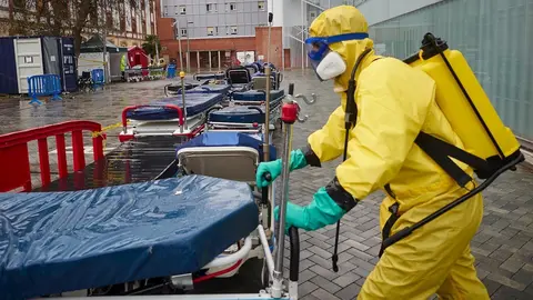 Voluntarios de la asociaci&oacute;n sin &aacute;nimo de lucro DYA desinfectan bajo la lluvia camillas en las inmediaciones del Complejo Hospitalario de Navarra prevenir la expansi&oacute;n del coronavirus. En Pamplona, (Navarra), a 21 de abril de 2020.