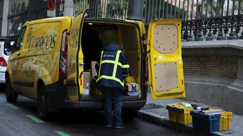 Un trabajador de Correos extrae de su furgoneta paquetes y cartas 