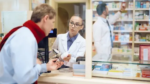 Farmacia. Farmacia de guardia. Paciente en una farmacia. Farmac&eacute;utica atiende a un paciente.