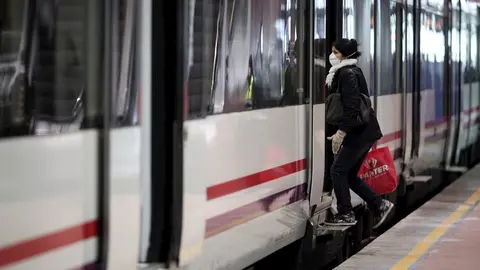 Viajeros entran en un tren de Cercan&iacute;as de Atocha portando mascarilla