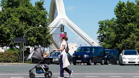 Una madre pasea a su hijo con el puente de la Barqueta detr&aacute;s,  un d&iacute;a despu&eacute;s de que el Gobierno de Espa&ntilde;a anunciara las medidas de desescalada por la pandemia del coronavirus, (Covid-19). En Sevilla (Andaluc&iacute;a, Espa&ntilde;a), a 29 de abril de 2020.