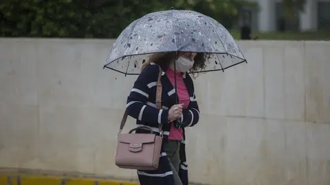 Una mujer con paraguas y mascarilla, durante la alerta amarilla por lluvia