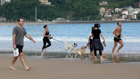 Varias persona caminan y corren con perros en la playa de La Concha en el d&iacute;a en que el Gobierno permite salir a hacer deporte de forma individual y pasear con otra persona con la que se conviva. En San Sebasti&aacute;n / Guip&uacute;zcoa (Espa&ntilde;a), a 2 de mayo de 2020.