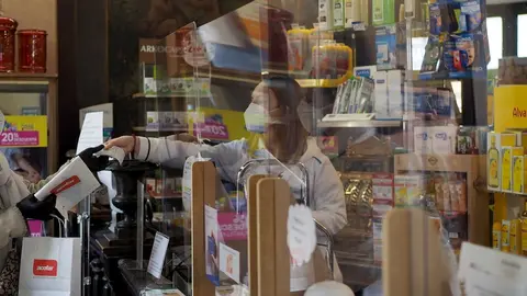 Una persona es atendida por una trabajadora de una farmacia de Vitoria, durante el d&iacute;a 46 de estado de alarma por la crisis del Covid-19, donde los movimientos est&aacute;n permitidos tan solo a menores de 14 a&ntilde;os, personas que no puedan teletrabajar o todos aqu