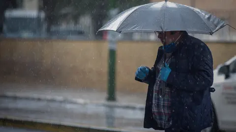 Un hombre camina bajo la lluvia protegido con un paraguas, durante la alerta amarilla. En el estado de alarma por la crisis del coronavirus, (Covid-19). En Sevilla, (Andaluc&iacute;a, Espa&ntilde;a), a 27 de abril de 2020.