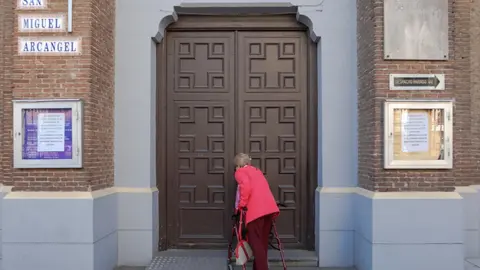 Una mujer intenta entrar en una iglesia con un cartel que indica que permanecer&aacute;