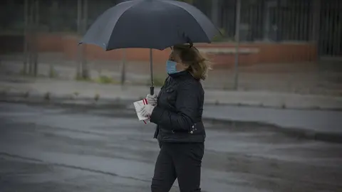 Una mujer bajo un paraguas en Sevilla durante el Estado de Alarma por la crisis del coronavirus, el dia 27 de abril de 2020